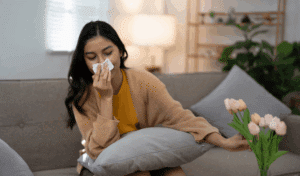 A person with allergies sitting on a couch using a tissue