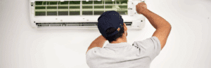 an hvac repair technician working on a wall-mounted air conditioning unit