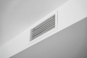 White ceiling air vent grille in modern home interior, clean HVAC ventilation system