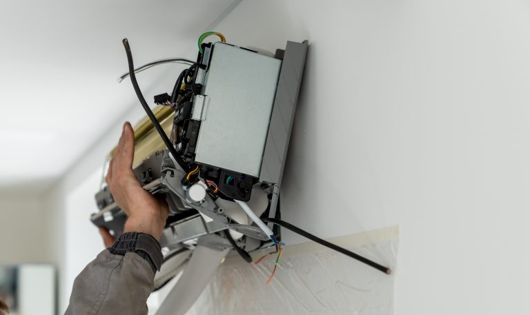 Man technician worker in uniform fixing repairing apartment air conditioner, installing wall-mounted mini split. AC unit maintenance concept