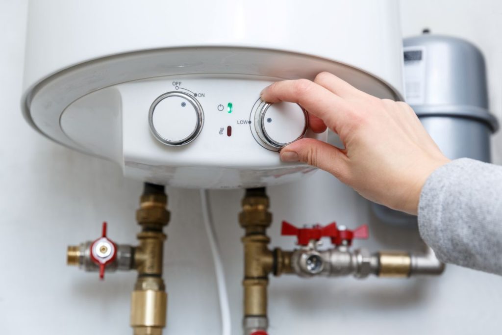 Female-hand-puts-thermostat-of-electric-water-heater-boiler-in-low-low-power-consumption-mode