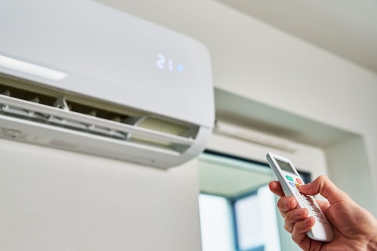 Hand-adjusting-temperature-on-air-conditioner-with-remote-control